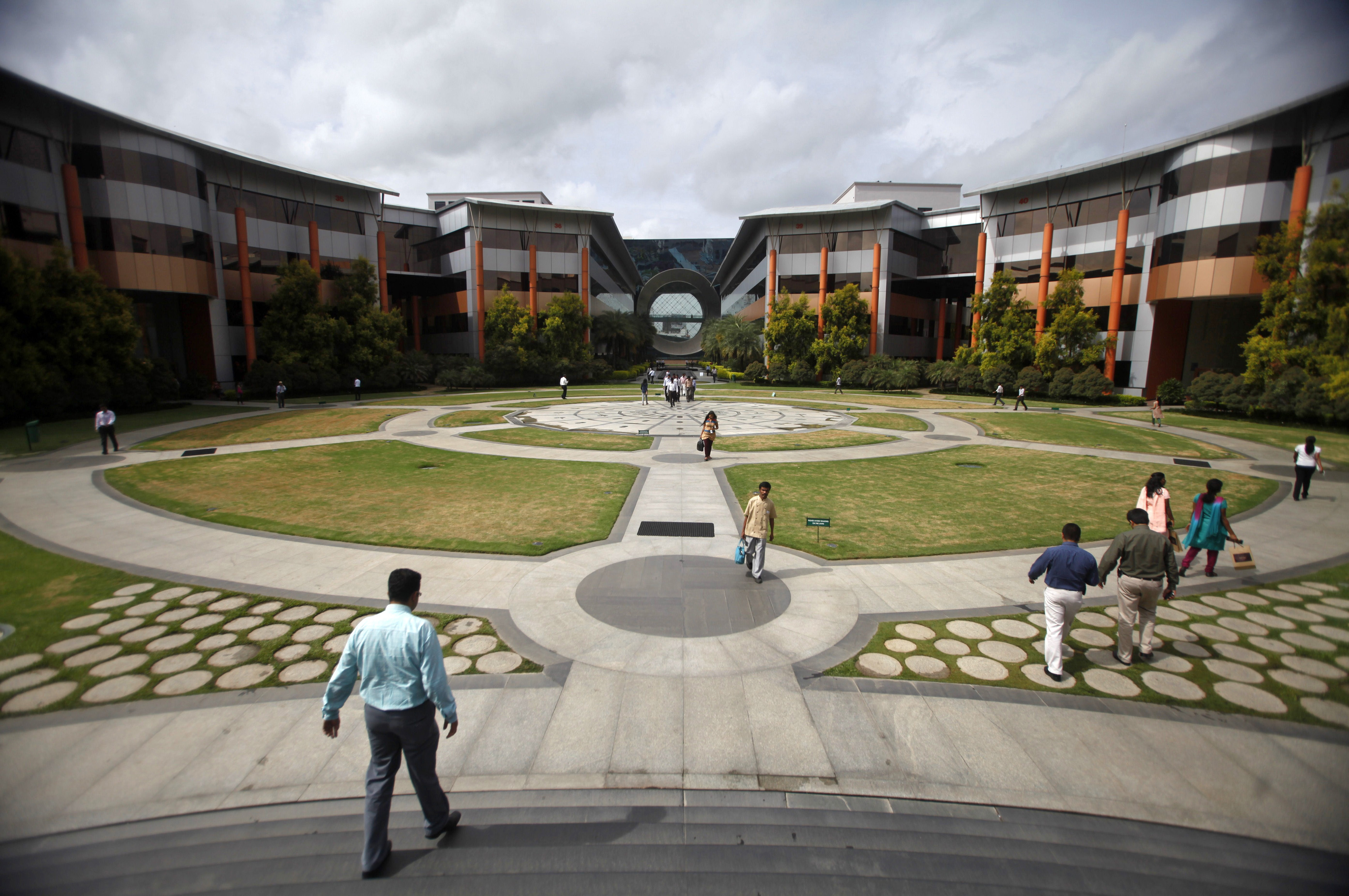 Employees walk in a forecourt at the Infosys campus in the Electronic City area of Bangalore