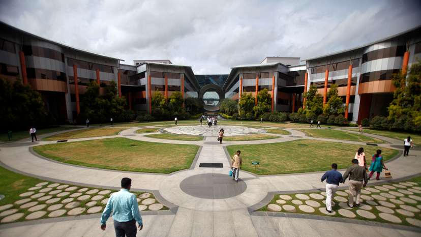 Employees walk in a forecourt at the Infosys campus in the Electronic City area of Bangalore
