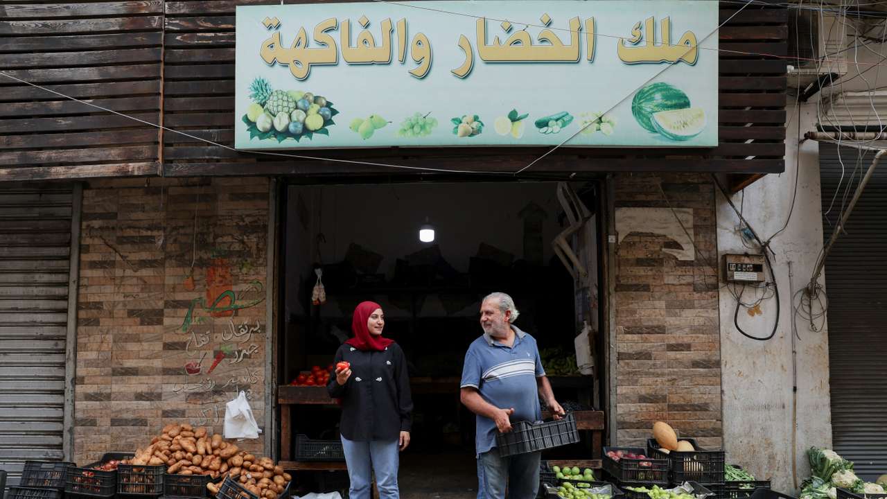 Fruits and vegetable shop owner Hussein Fakih and his daughter Alaa, stand in front of their shop in Bourj Hammoud
