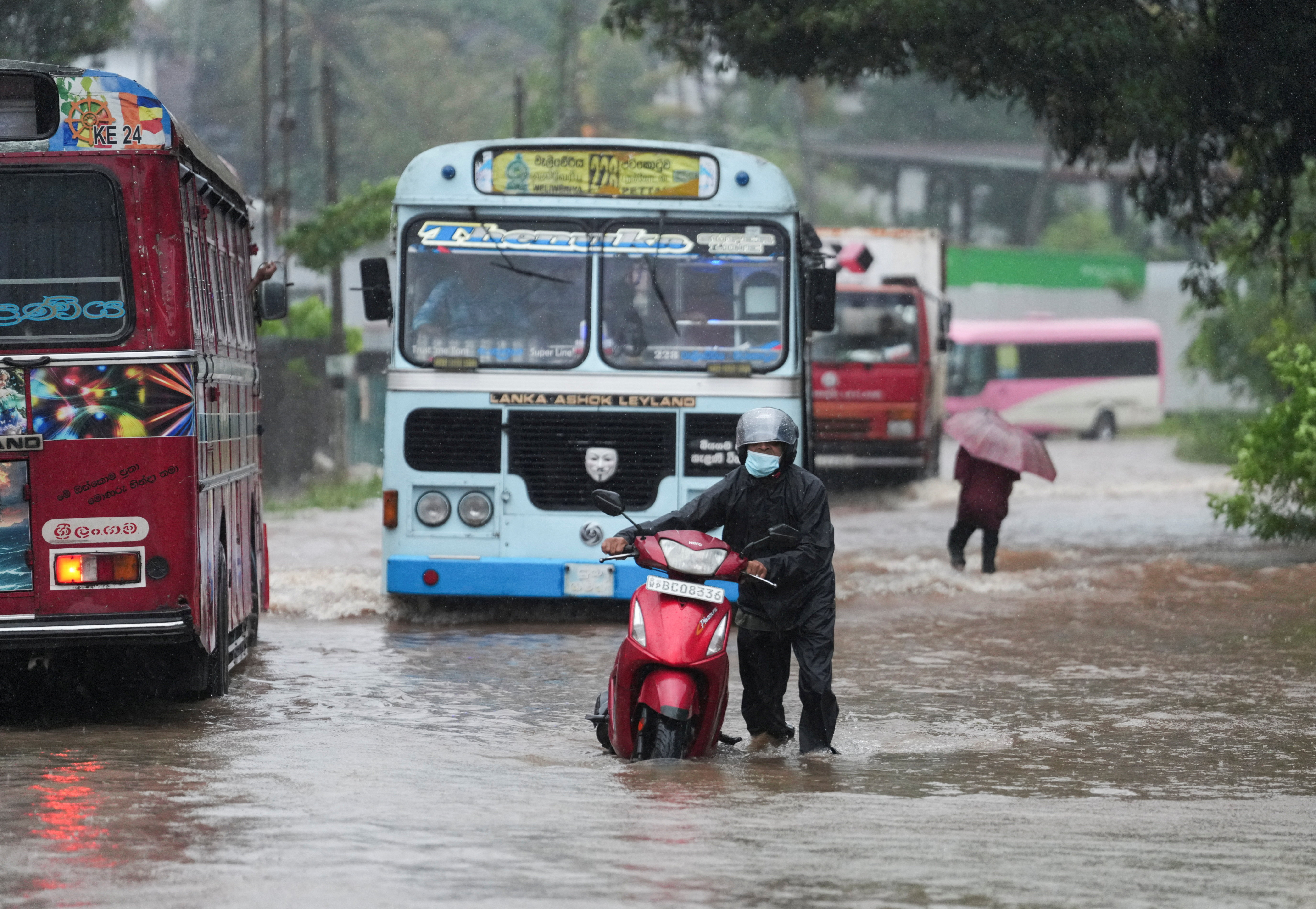 People and vehicles wade through a waterlogged street following heavy rainfall in Kelaniya