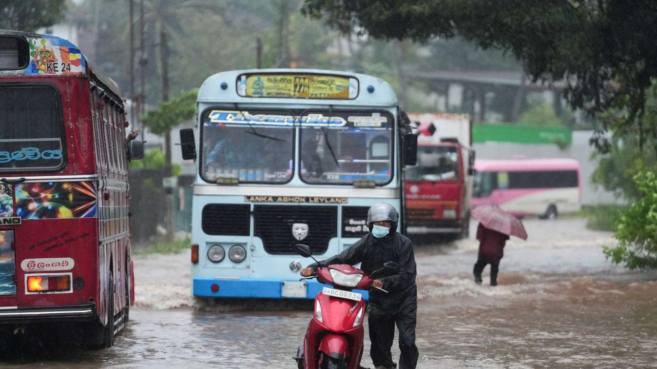 People and vehicles wade through a waterlogged street following heavy rainfall in Kelaniya