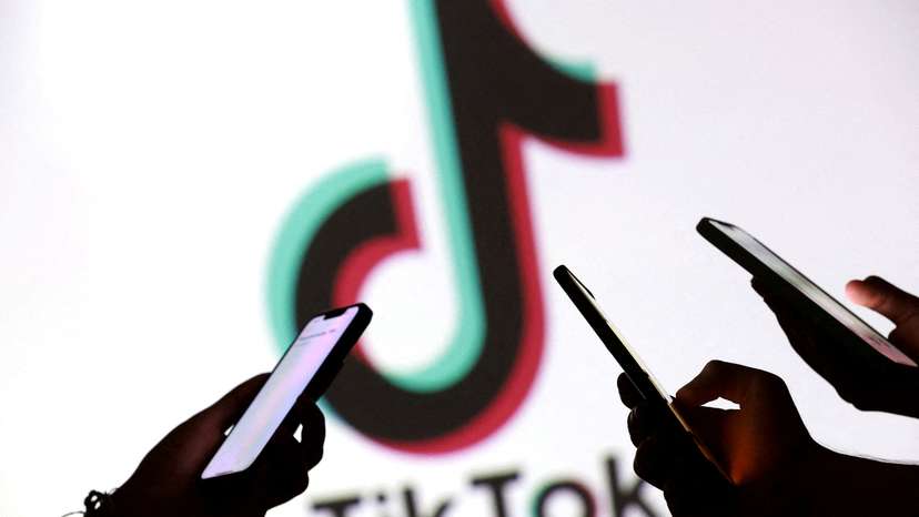 FILE PHOTO: Illustration shows teenagers pose for a photo while holding smartphones in front of a TikTok logo