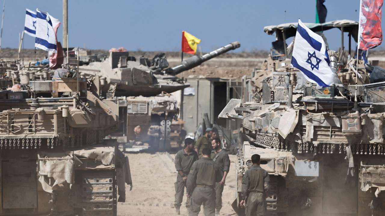 Israeli soldiers stand next to tanks near the Israel-Gaza border, in Israel