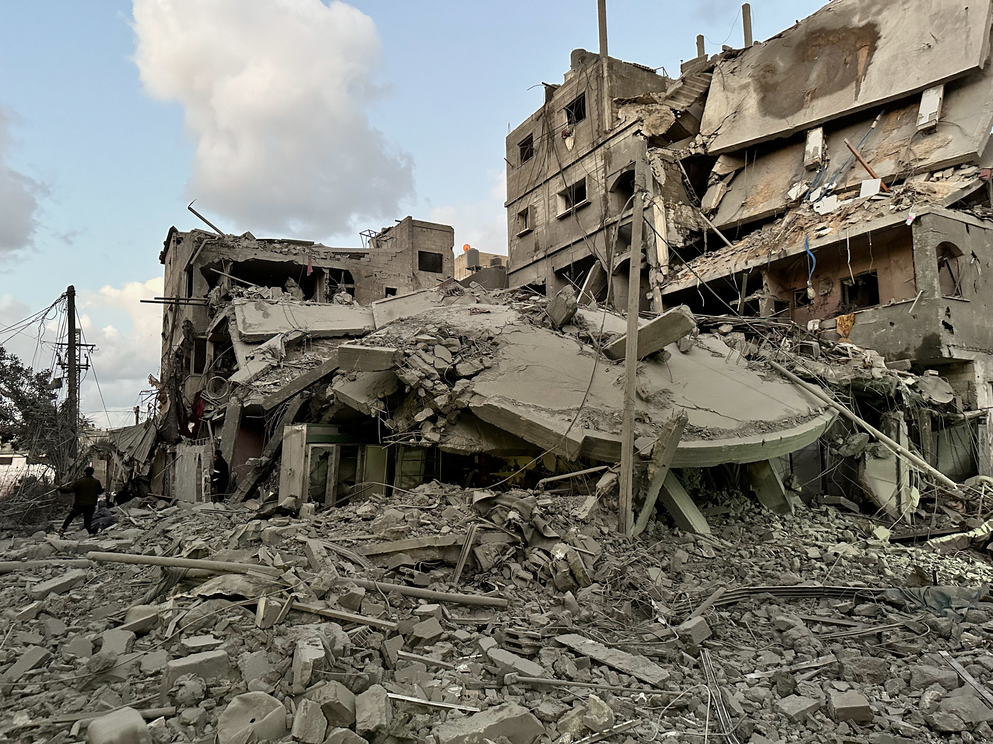Palestinians walk at the site of Israeli strikes on houses, in Jabalia refugee camp