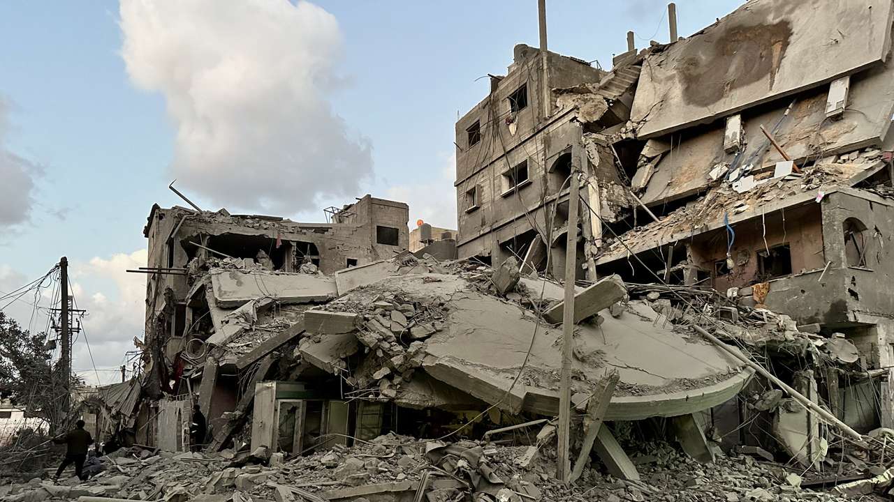 Palestinians walk at the site of Israeli strikes on houses, in Jabalia refugee camp