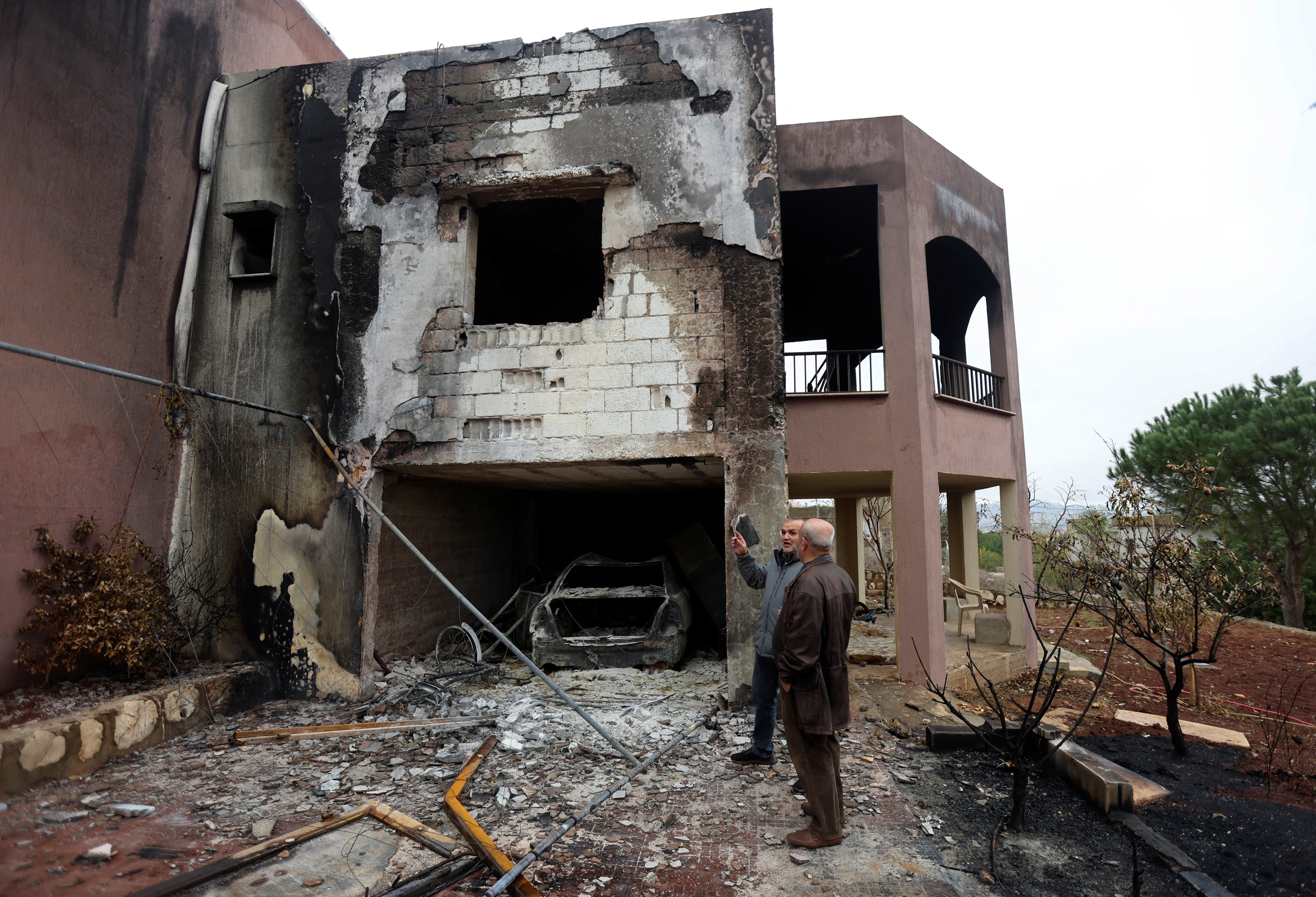 Resident Kamal Rizk chats with Abdel al-Moneim Choukair, head of the municipality in the town of Mays al-Jabal, outside his damaged house in the town