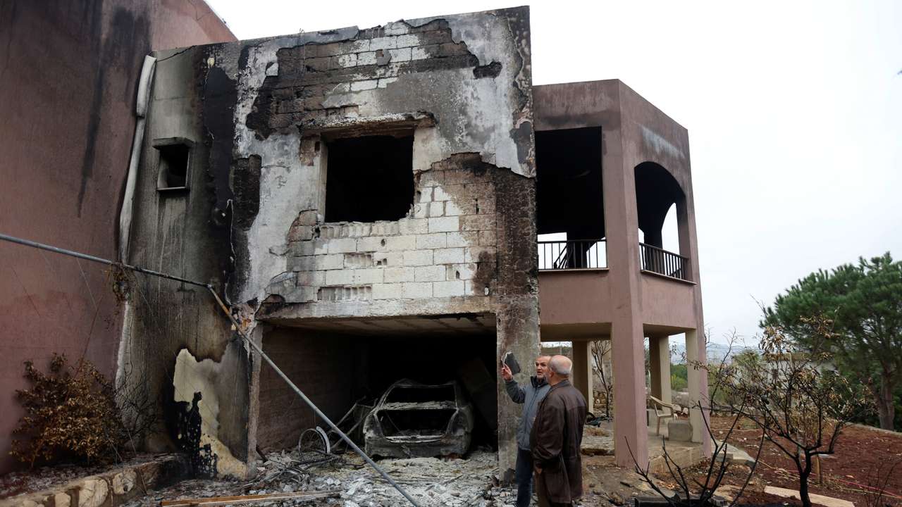 Resident Kamal Rizk chats with Abdel al-Moneim Choukair, head of the municipality in the town of Mays al-Jabal, outside his damaged house in the town