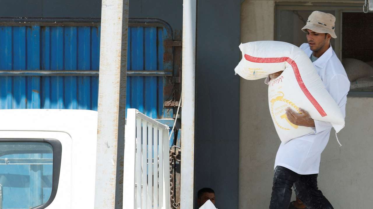 A worker loads a 50 kg sack of wheat flour into a pick-up truck at Wadi Al-Sanabul Mill, on the outskirts of Baghdad