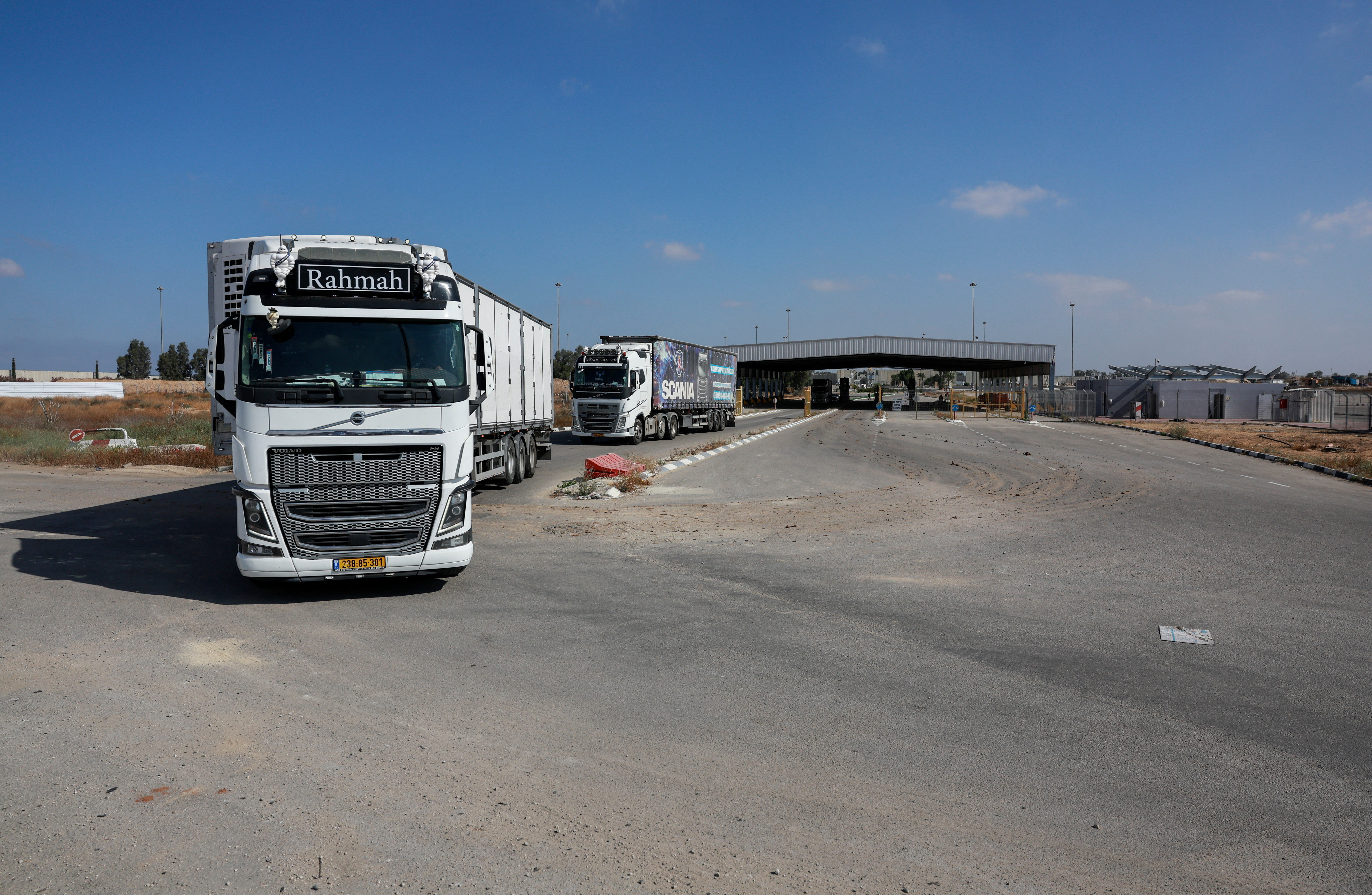 Trucks carrying aid drive at the Kerem Shalom crossing between Israel and Gaza, before going into Gaza, on the Israeli side of the Israel-Gaza border