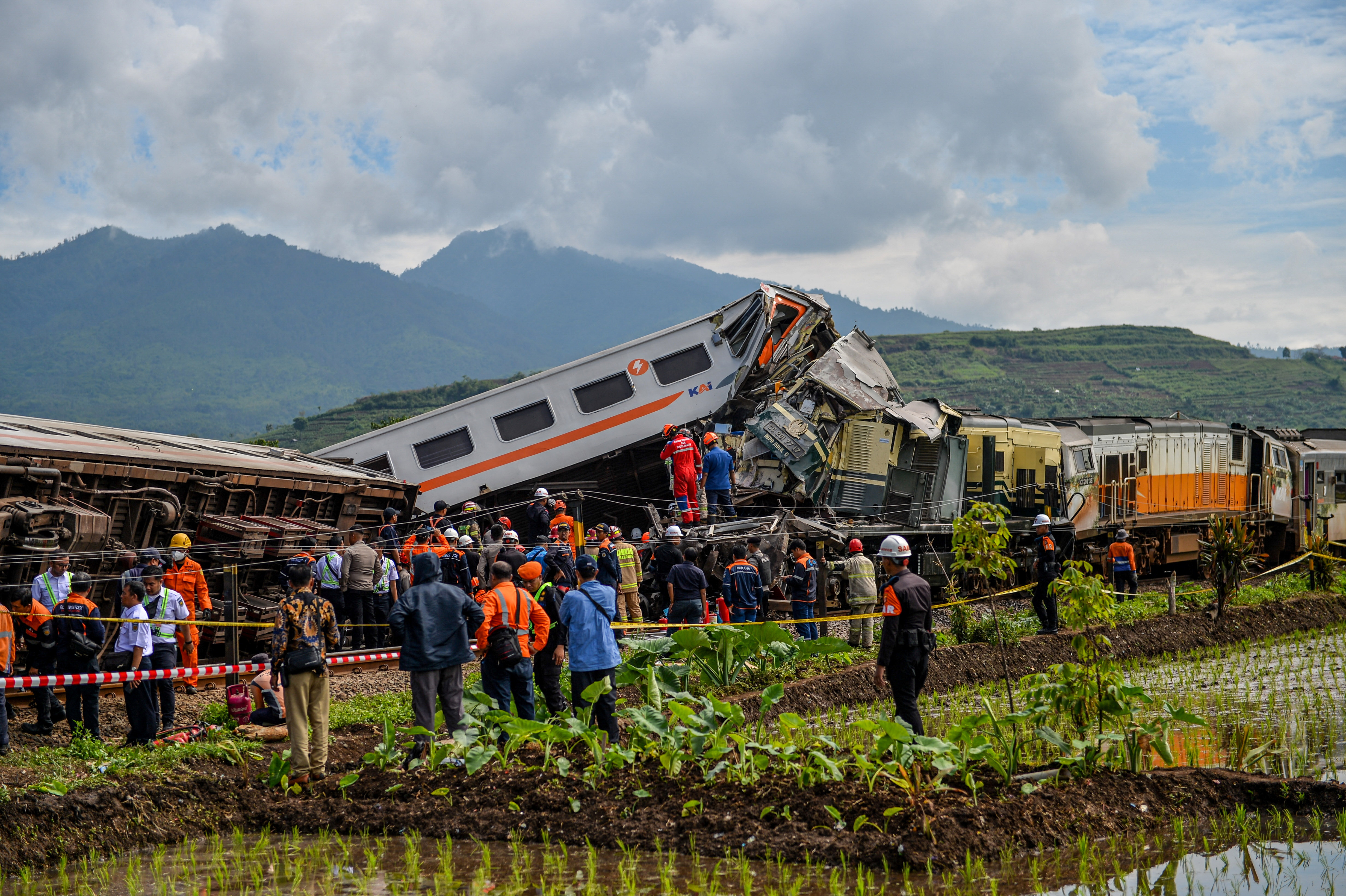People stand at the site of a train collision between the local Bandung Raya train and the Turangga train in Cicalengka