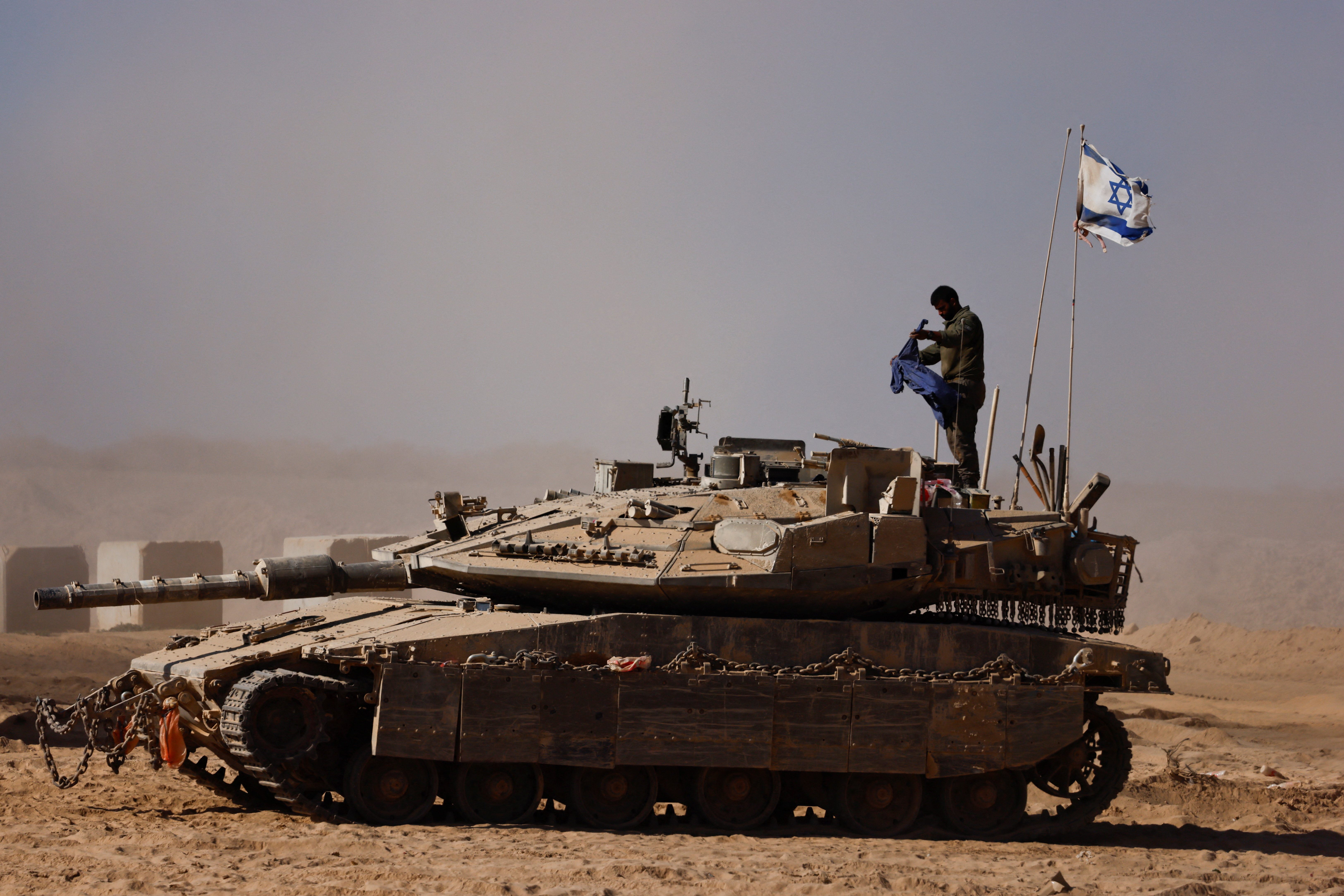An Israeli soldier stands on a tank on the Israeli side of the border with Gaza