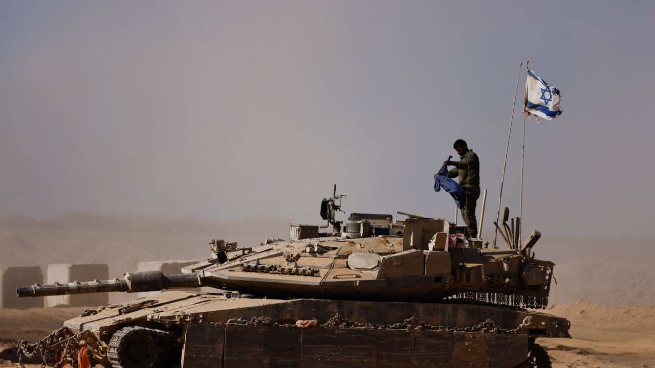 An Israeli soldier stands on a tank on the Israeli side of the border with Gaza