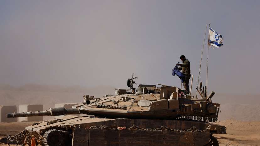 An Israeli soldier stands on a tank on the Israeli side of the border with Gaza