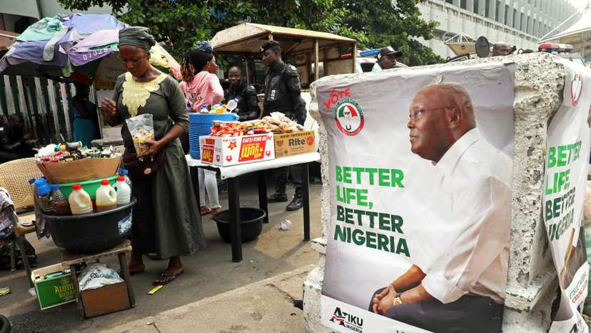 FILE PHOTO: A street vendor is pictured next to a campaign poster of Atiku Abubakar leader of the People's Democratic Party (PDP) in Lagos