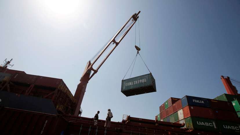 FILE PHOTO: Workers look on as a ship uses its crane to unload containers at a container terminal at the Red Sea port of Hodeidah