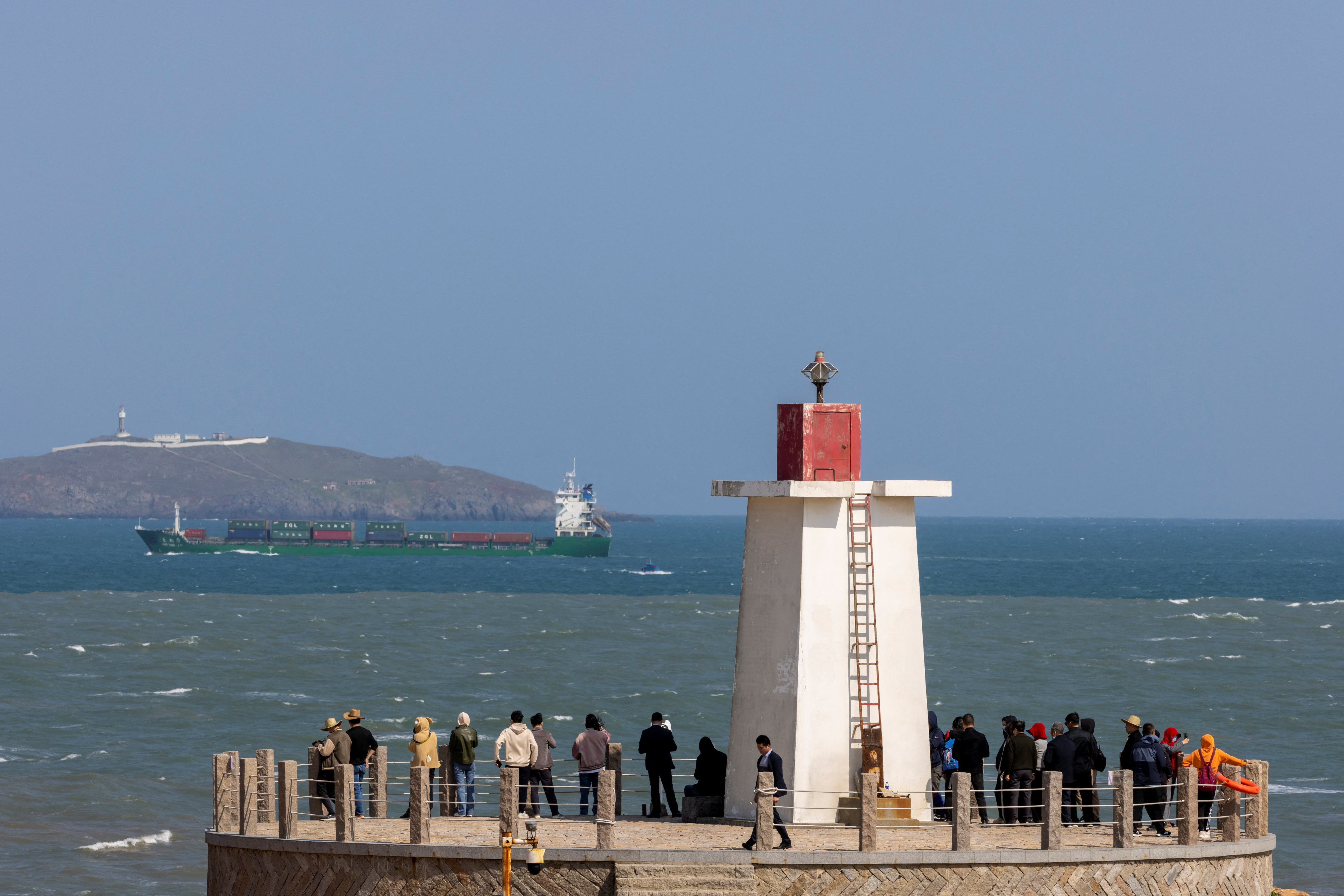 People look across the strait from a lighthouse at the 68-nautical-mile scenic spot, on Pingtan Island