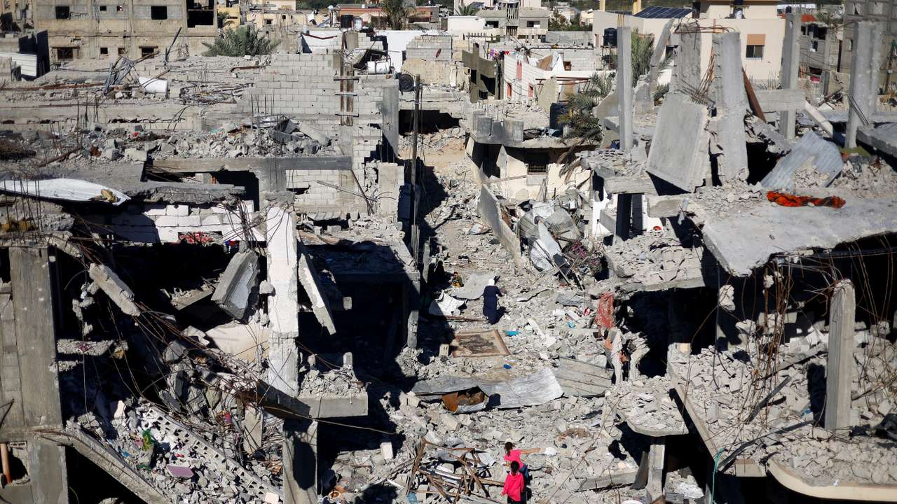 Palestinian children walk among the houses destroyed in Israeli strikes, at Khan Younis refugee camp