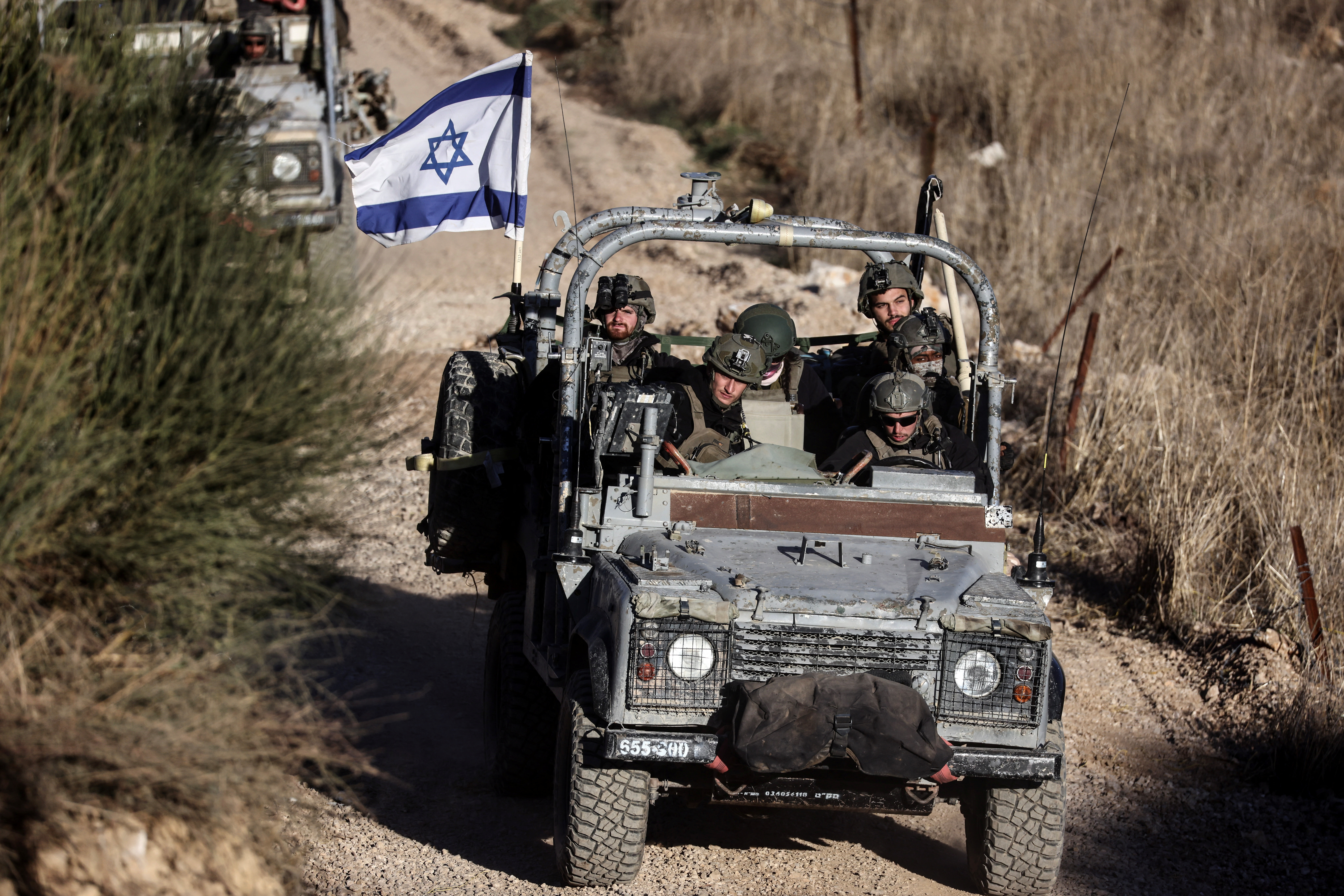Israeli military vehicles ride through Syria close to the ceasefire line between the Israeli-occupied Golan Heights and Syria, as seen from Majdal Shams in the Golan Heights