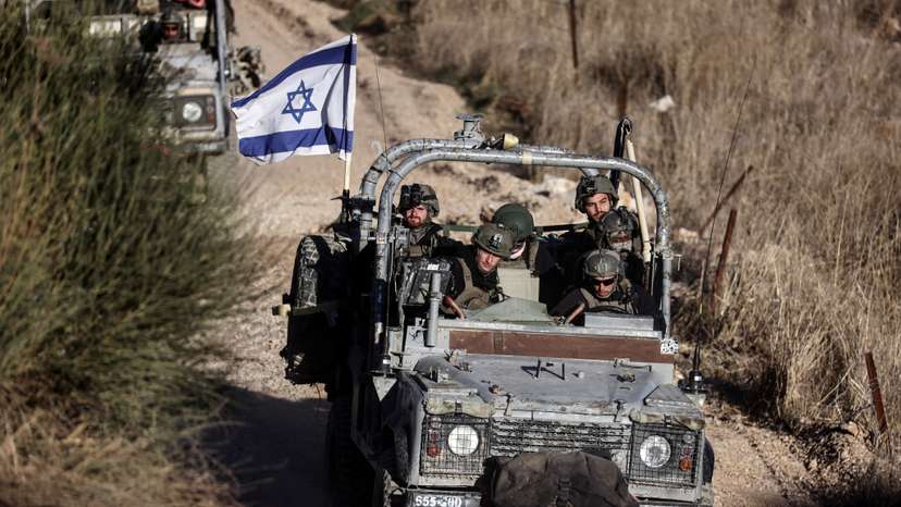Israeli military vehicles ride through Syria close to the ceasefire line between the Israeli-occupied Golan Heights and Syria, as seen from Majdal Shams in the Golan Heights