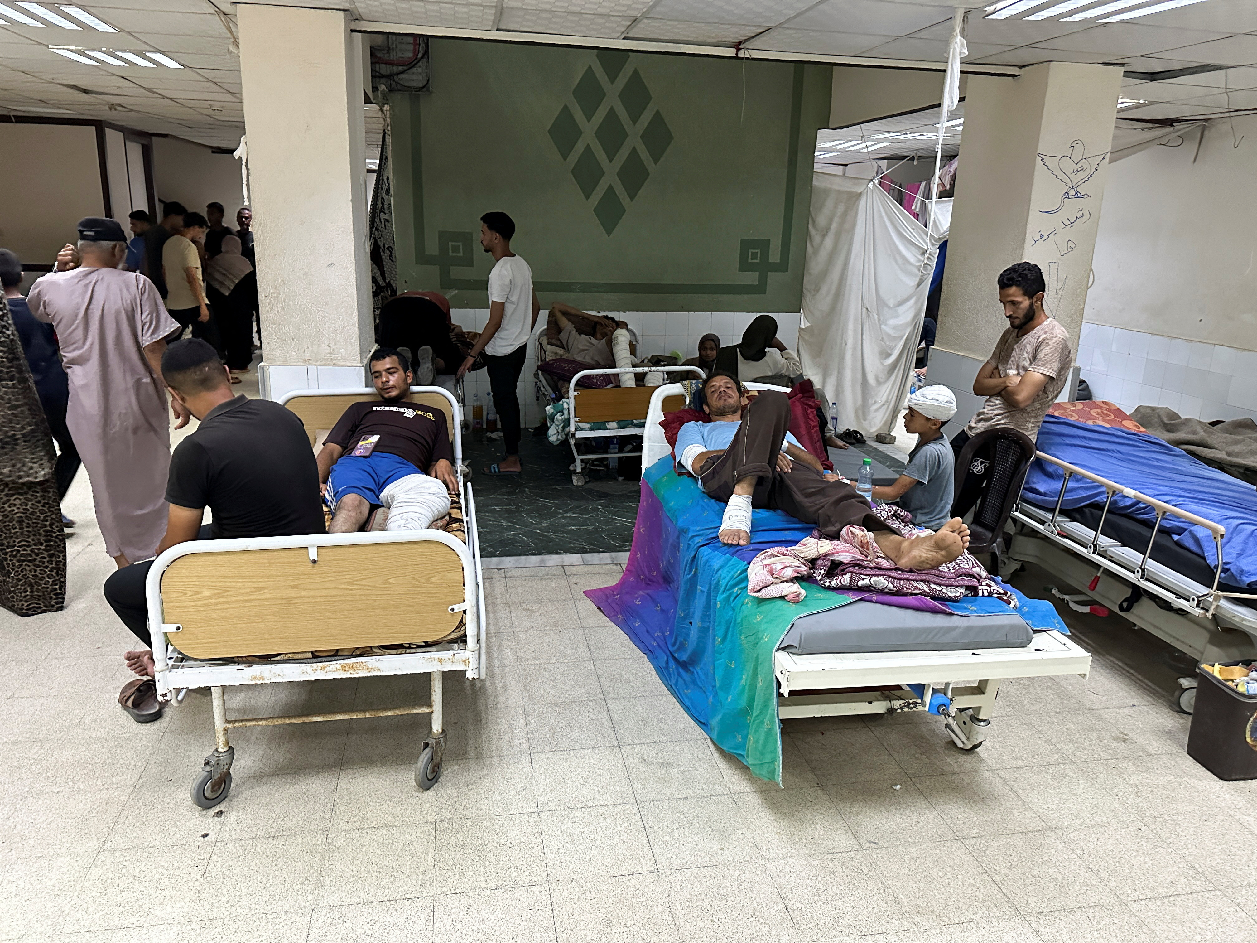Wounded Palestinians, who were injured in an Israeli strike, lie on beds as Gaza's overwhelmed Al-Aqsa hospital struggles to treat the wounded, amid the Israel-Hamas conflict, in Deir Al-Balah