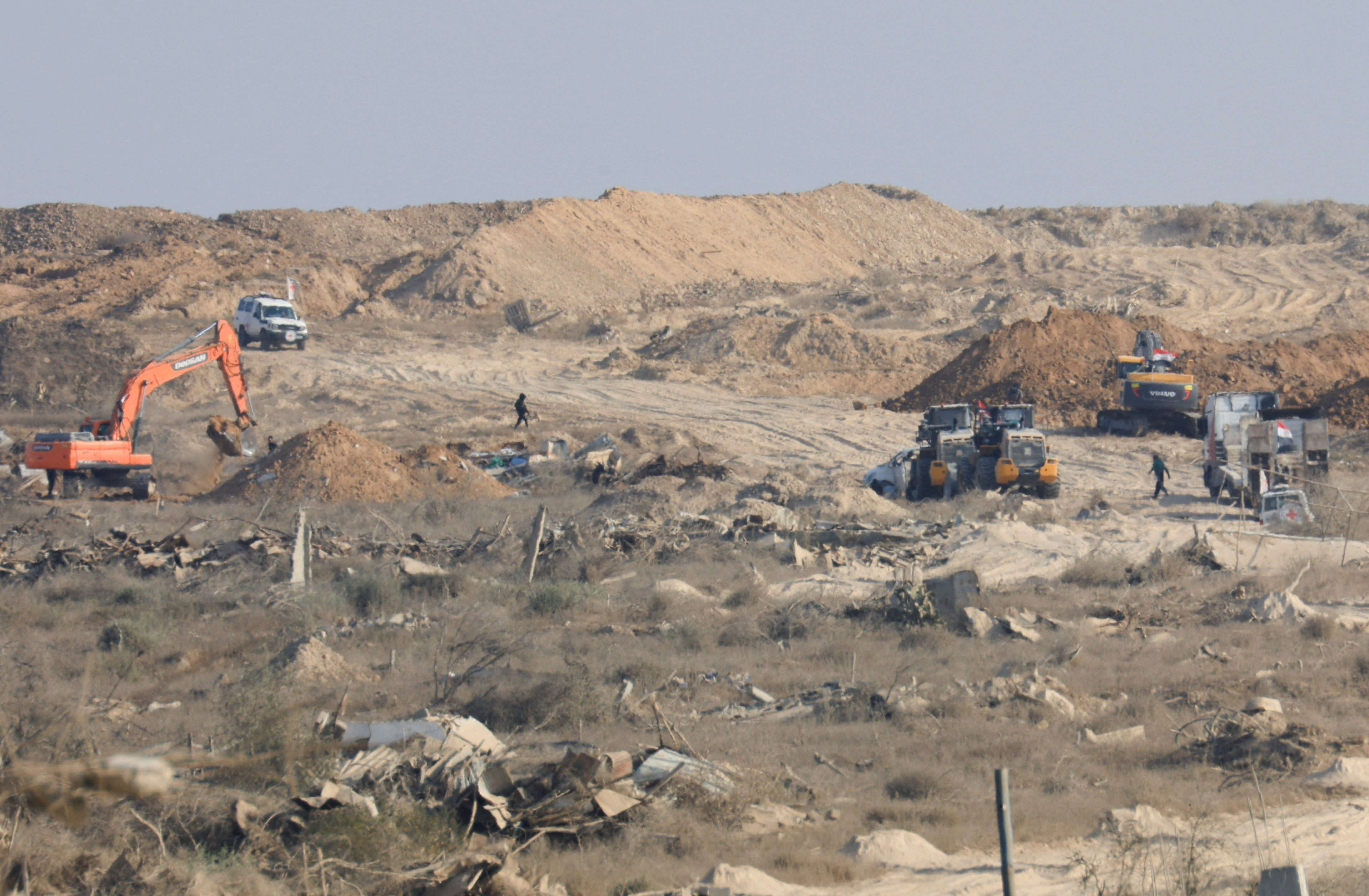 A machinery operates next to a Red Cross vehicle at an area within the so-called "yellow line" to which Israeli troops withdrew under the ceasefire, in Gaza City