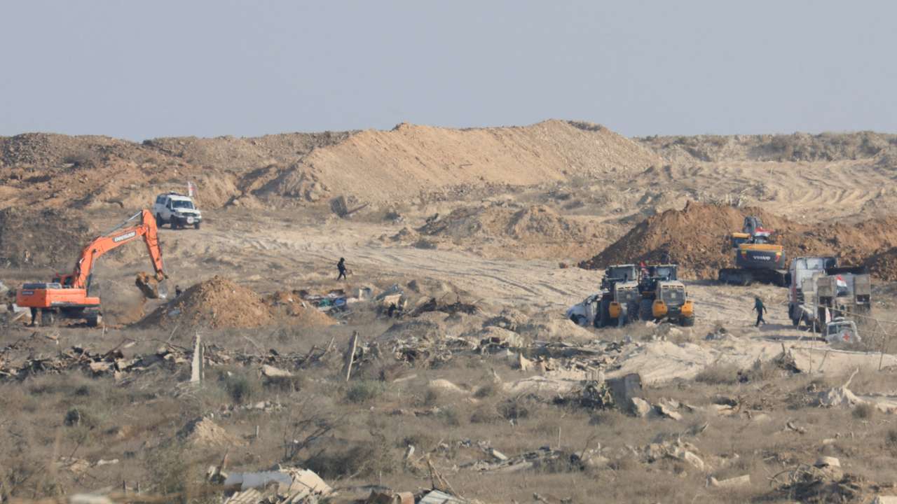 A machinery operates next to a Red Cross vehicle at an area within the so-called "yellow line" to which Israeli troops withdrew under the ceasefire, in Gaza City