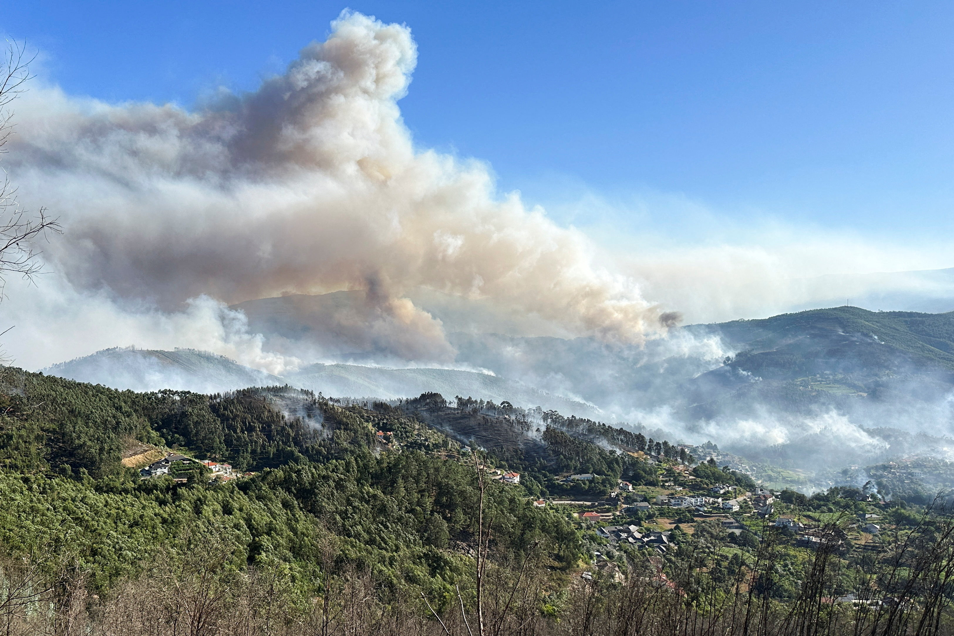 Smoke from a wildfire rises over the hills near the village of Canelas