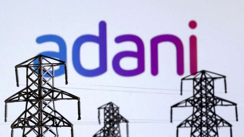 FILE PHOTO: Illustration shows Electric power transmission pylon miniatures and Adani Green Energy logo