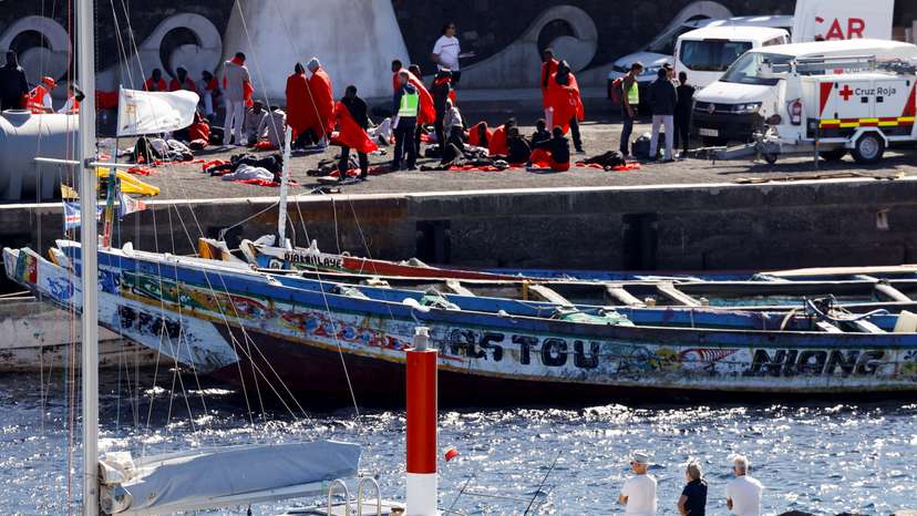 Several tourists observe migrants getting treated as they arrive, at the port of La Restinga