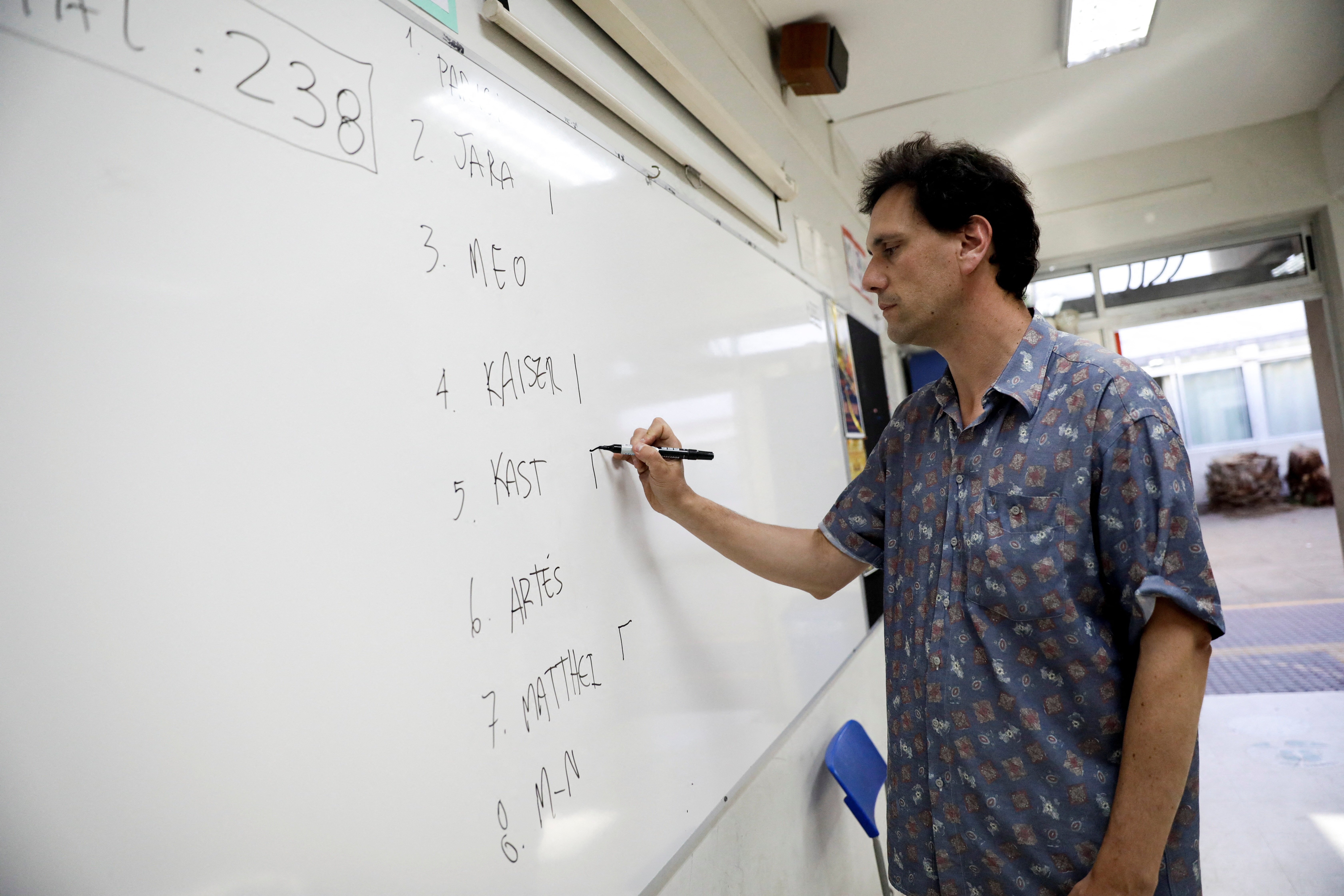 An electoral worker writes down the number of votes cast for each candidate after the polls closed in the presidential election, in Santiago, Chile, November 16, 2025. REUTERS/Juan Gonzalez