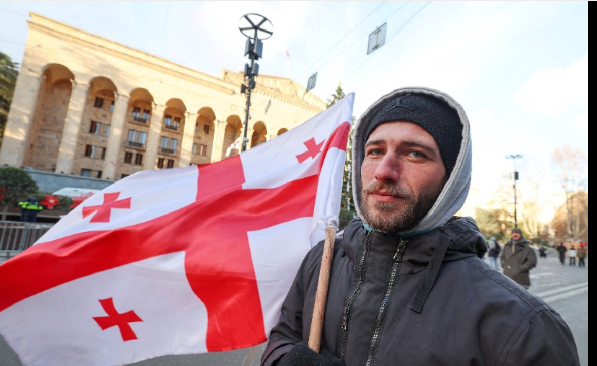 An anti-government demonstrator stands during a rally outside the parliament building as parliament members elect a new president in Tbilisi on December 14, 2024.