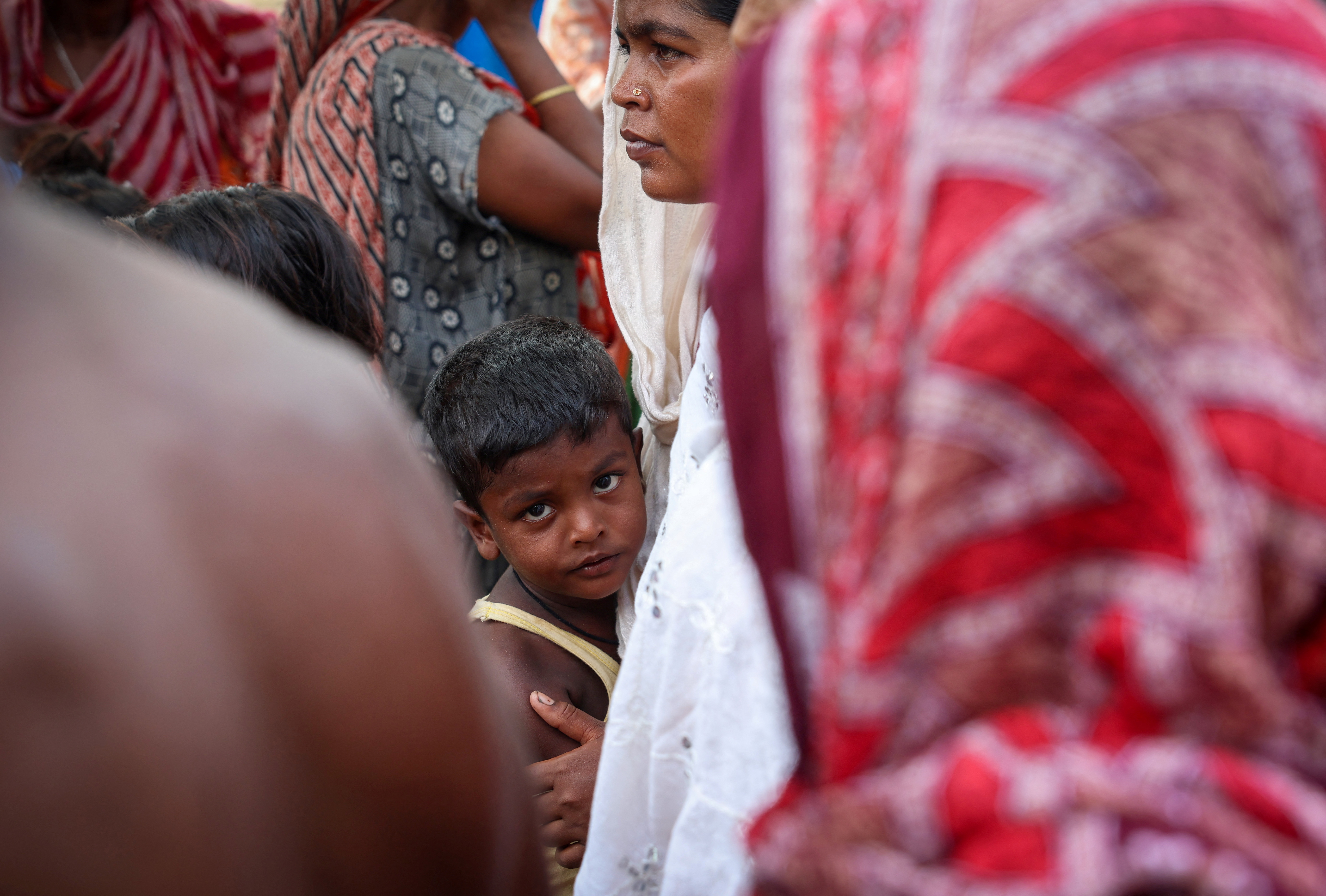 A boy stands with his mother inside a makeshift shelter camp in Goalpara district in the northeastern state of Assam