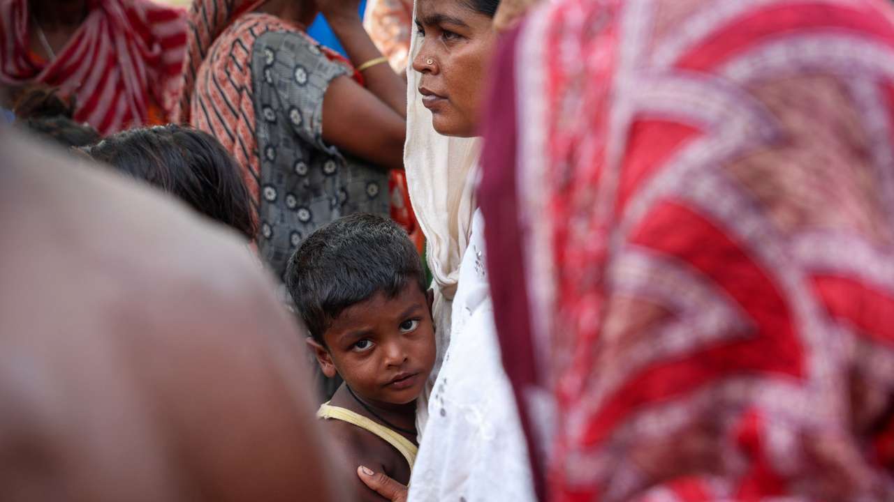 A boy stands with his mother inside a makeshift shelter camp in Goalpara district in the northeastern state of Assam