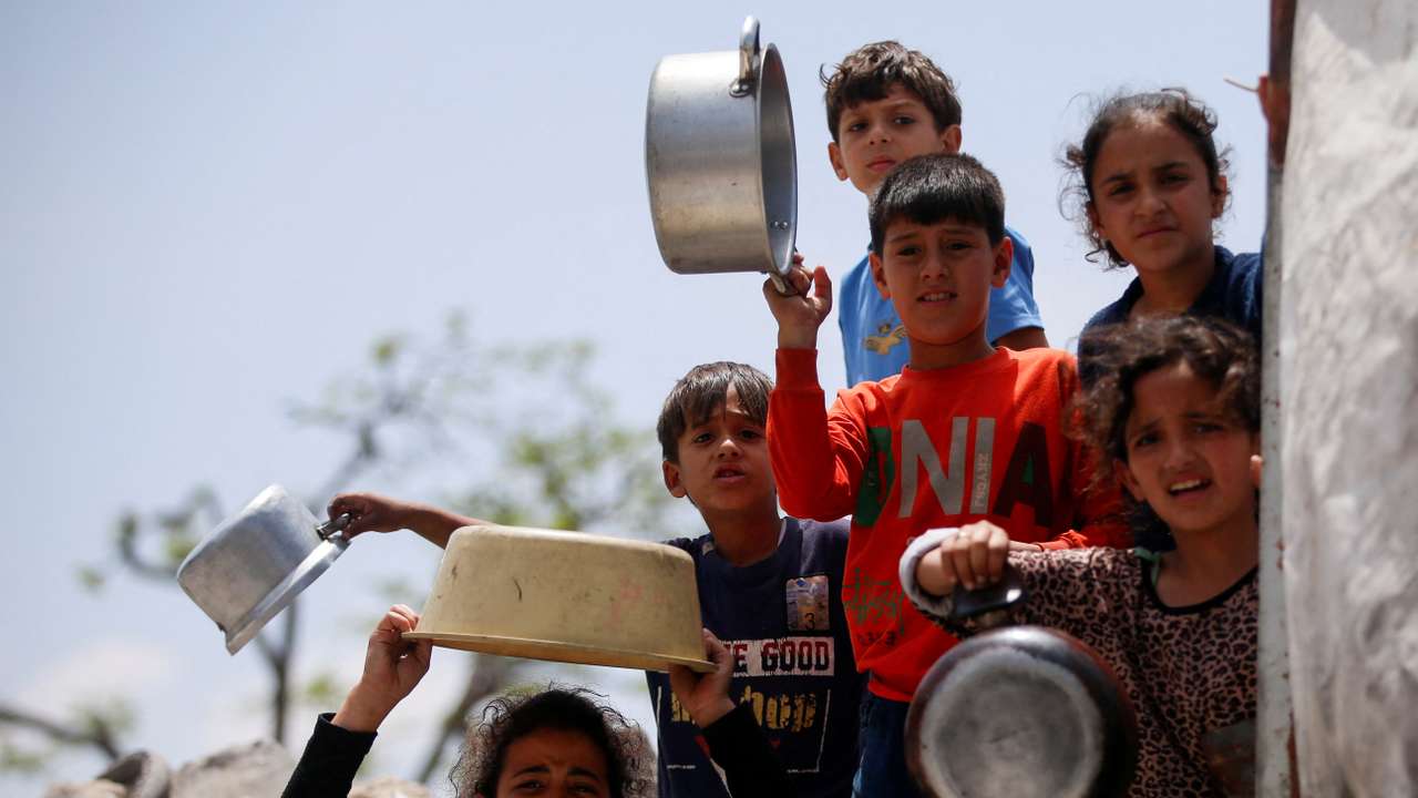 Palestinians wait to receive food cooked by a charity kitchen, in Jabalia