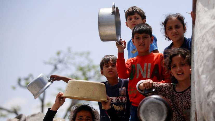 Palestinians wait to receive food cooked by a charity kitchen, in Jabalia