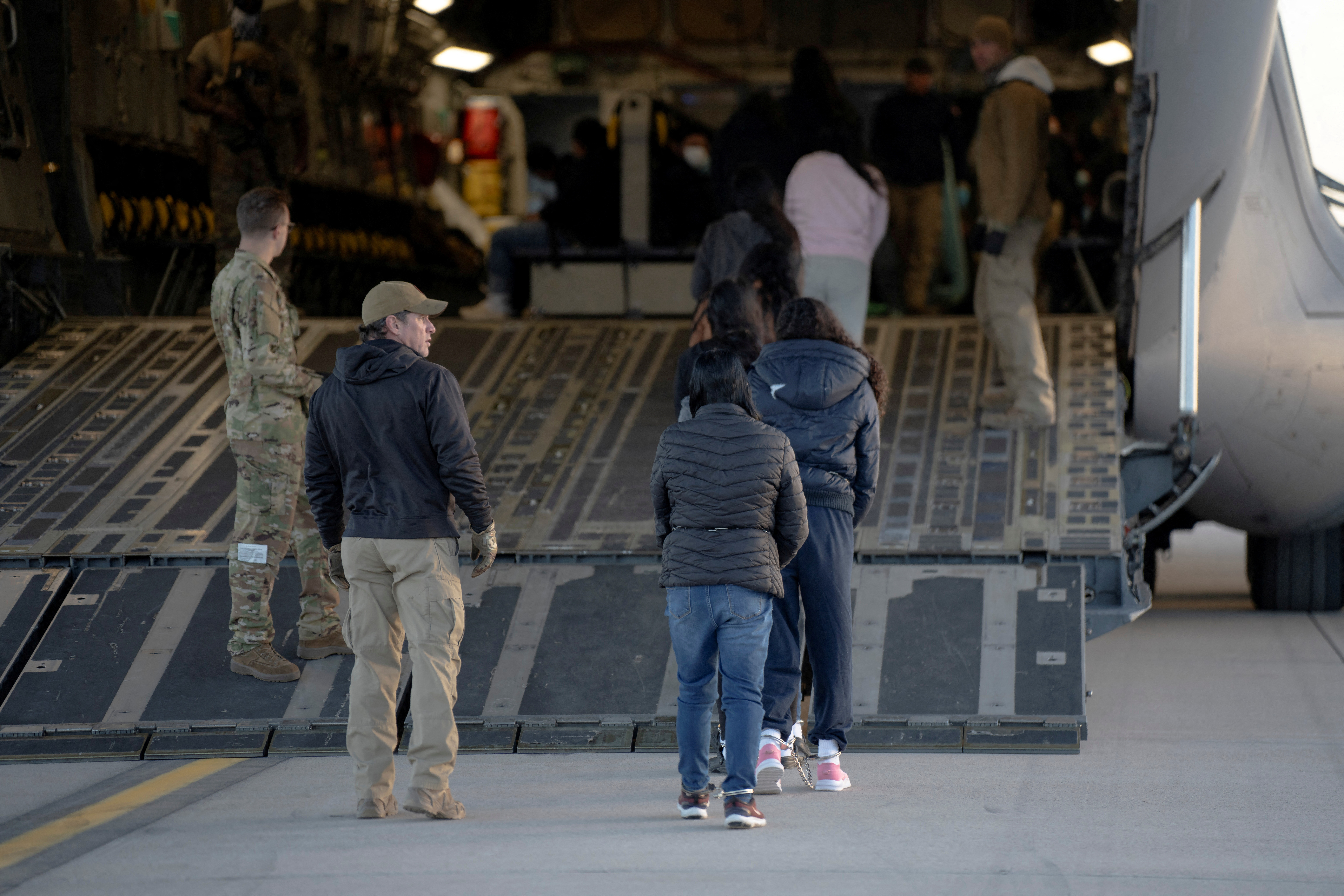 FILE PHOTO: U.S. Customs and Border Protection security agents guide a group of detained migrants to board a removal flight
