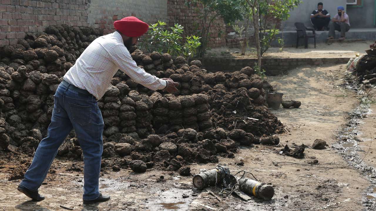 A man takes photographs of projectile debris in a courtyard of a residential house, following Pakistani military strikes, at Wadala Bhitewadh