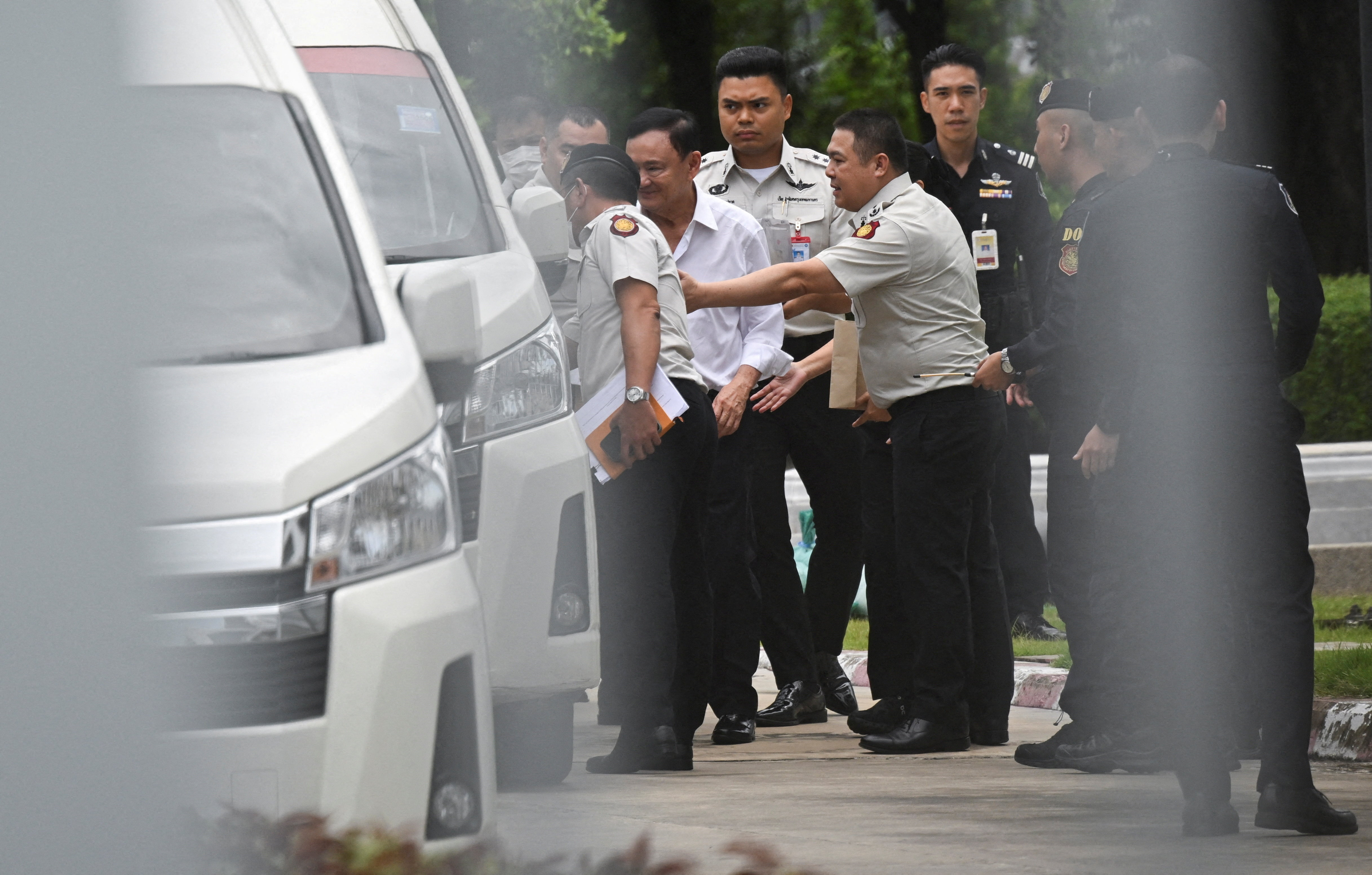 Former Thai Prime Minister Thaksin Shinawatra is escorted by corrections officers in Bangkok