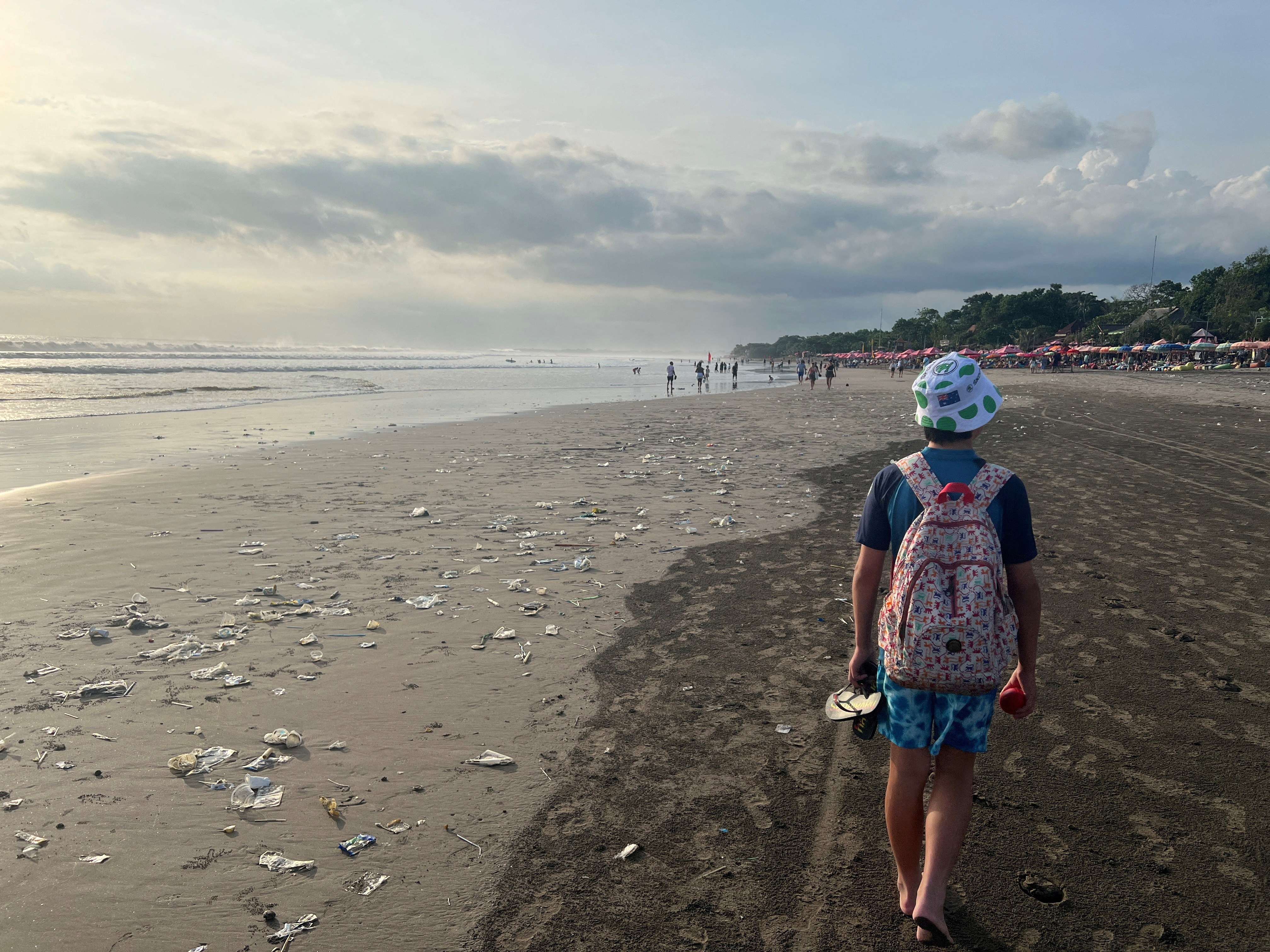 FILE PHOTO: A boy walks on a beach polluted by plastic trash in Bali