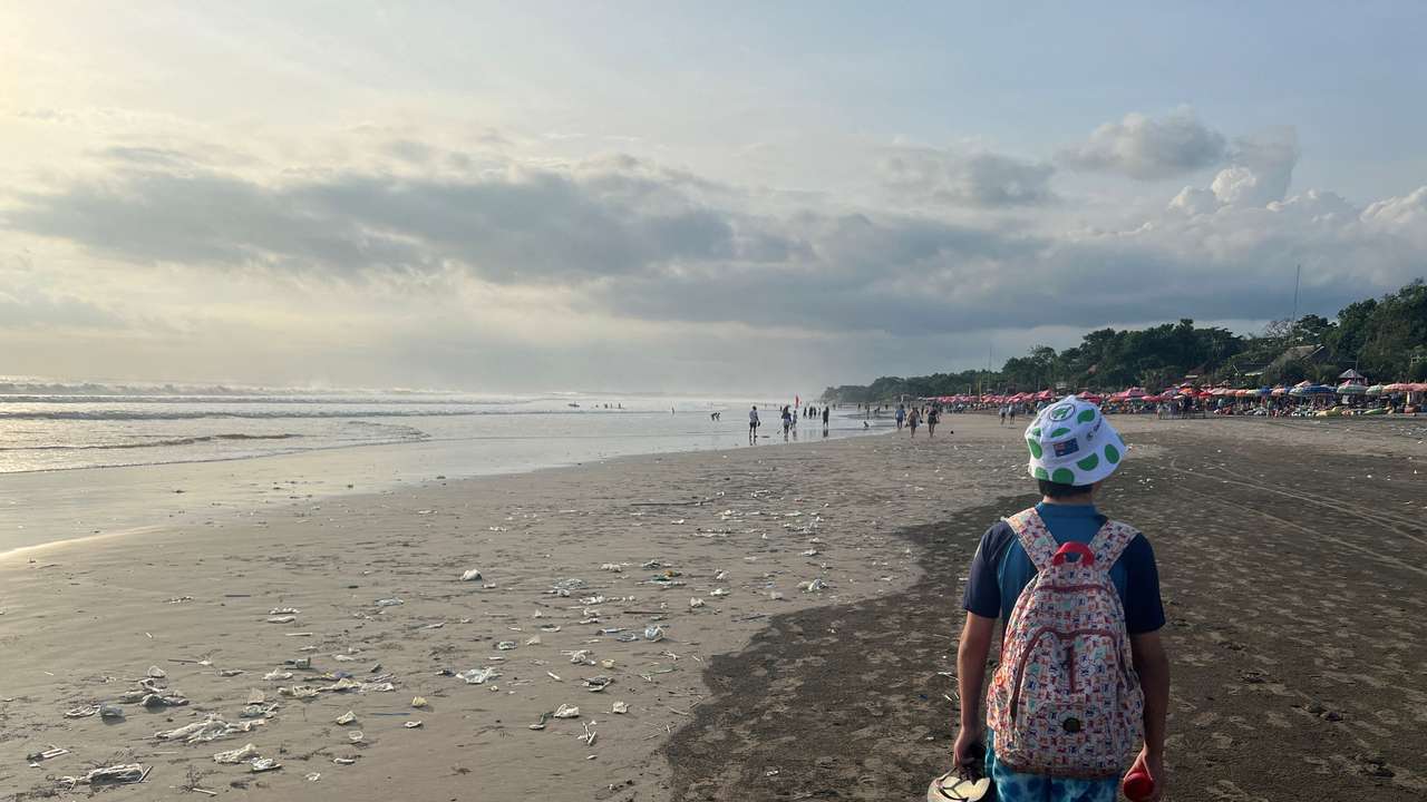 FILE PHOTO: A boy walks on a beach polluted by plastic trash in Bali