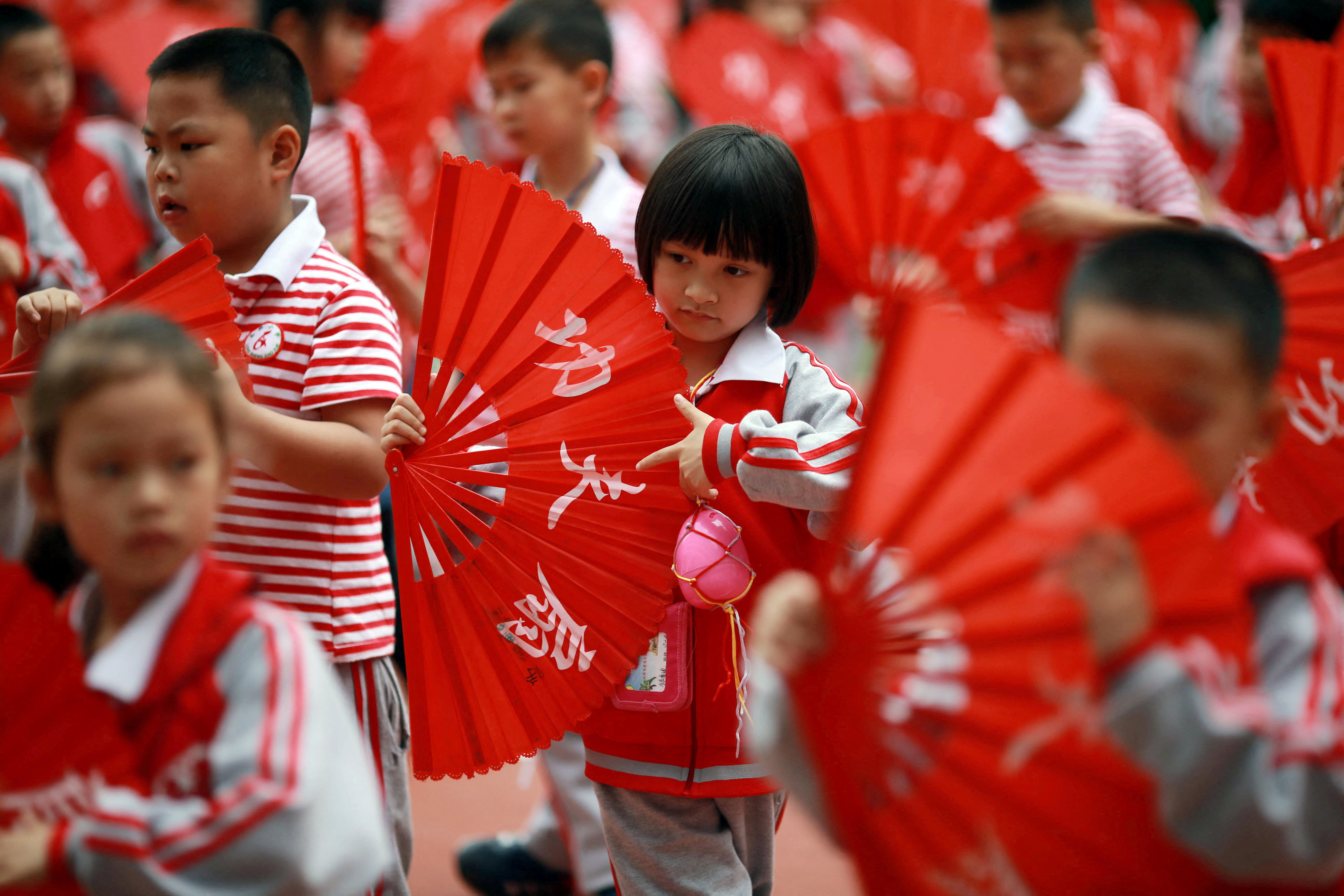 Children perform a Kung Fu Fan dance while carrying plastic eggs during the "egg protection" activity designed by the school for its students to understand motherhood in Guilin