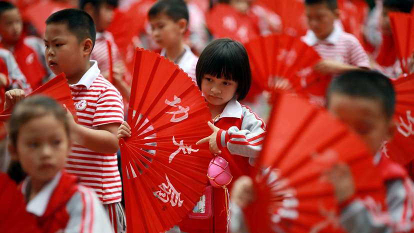 Children perform a Kung Fu Fan dance while carrying plastic eggs during the "egg protection" activity designed by the school for its students to understand motherhood in Guilin