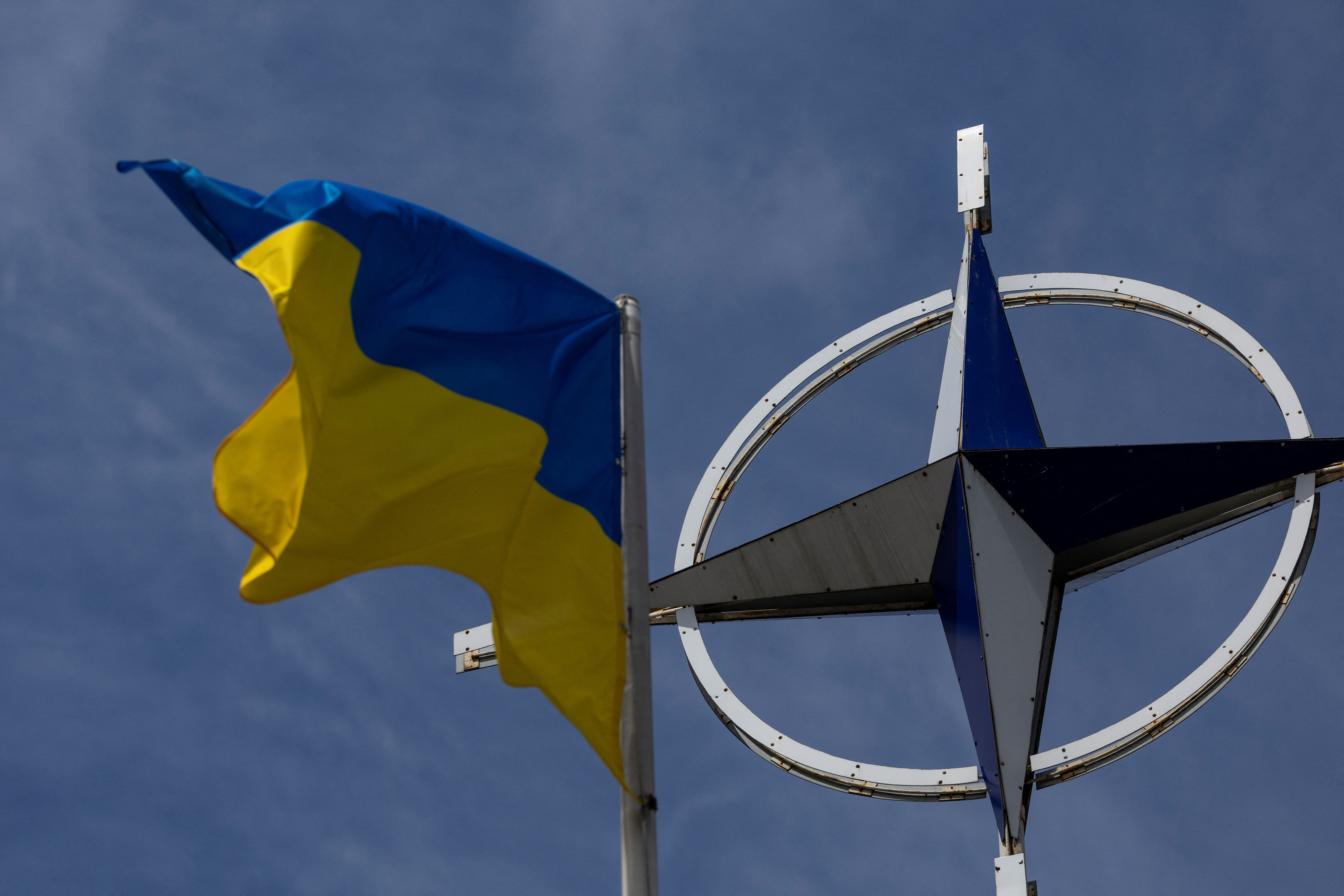 Ukrainian national flag rises in front of the NATO emblem in central Kyiv