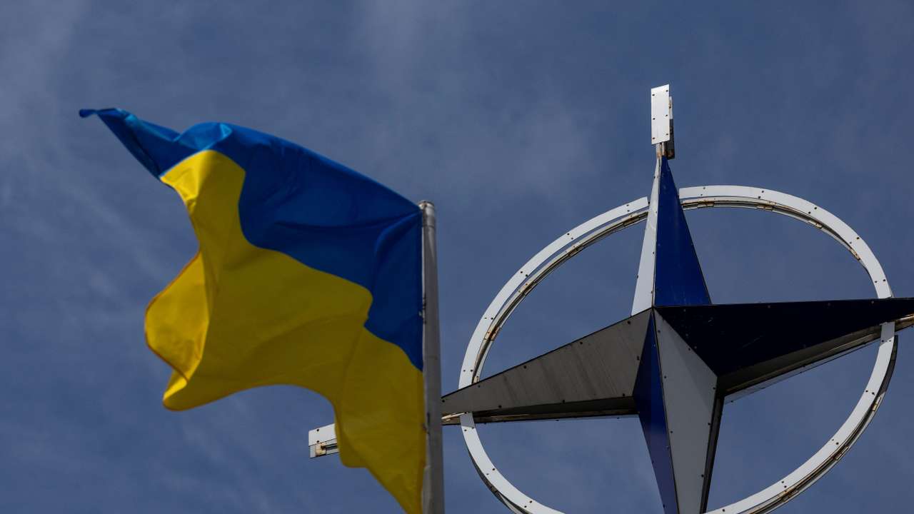 Ukrainian national flag rises in front of the NATO emblem in central Kyiv