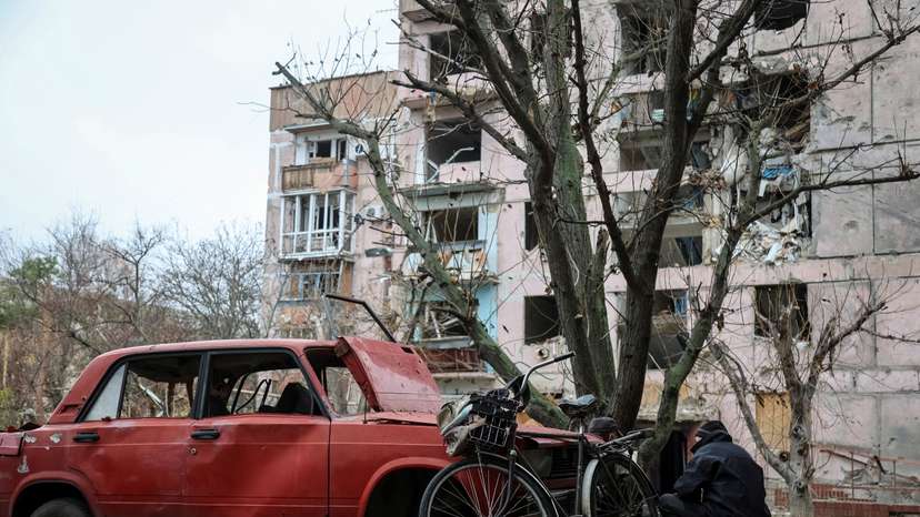 A resident hides from a Russian FPV drone behind a damaged car in the frontline town of Huliaipole