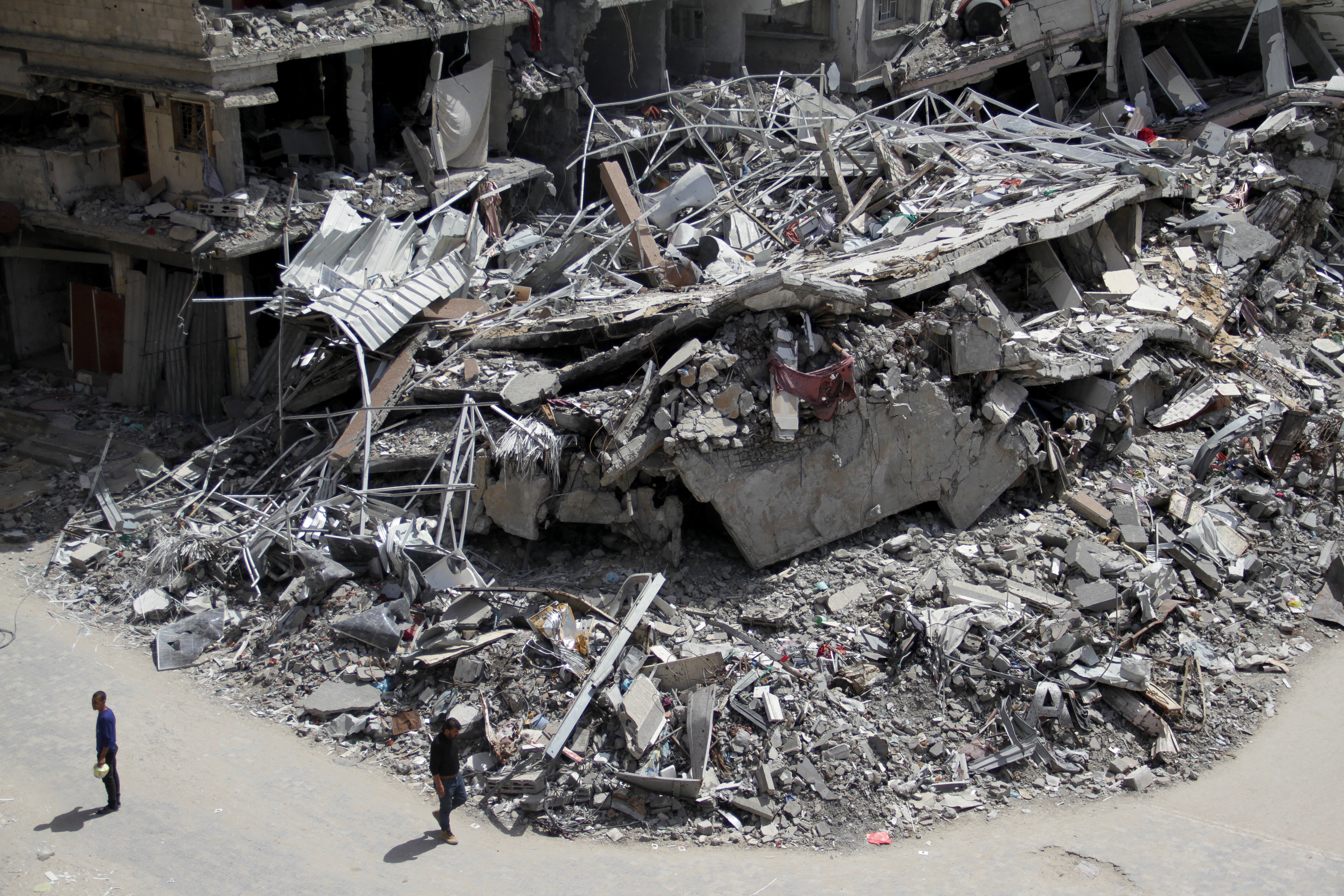 Palestinians walk past the ruins of houses and buildings destroyed during Israel’ military offensive, in the northern Gaza Strip