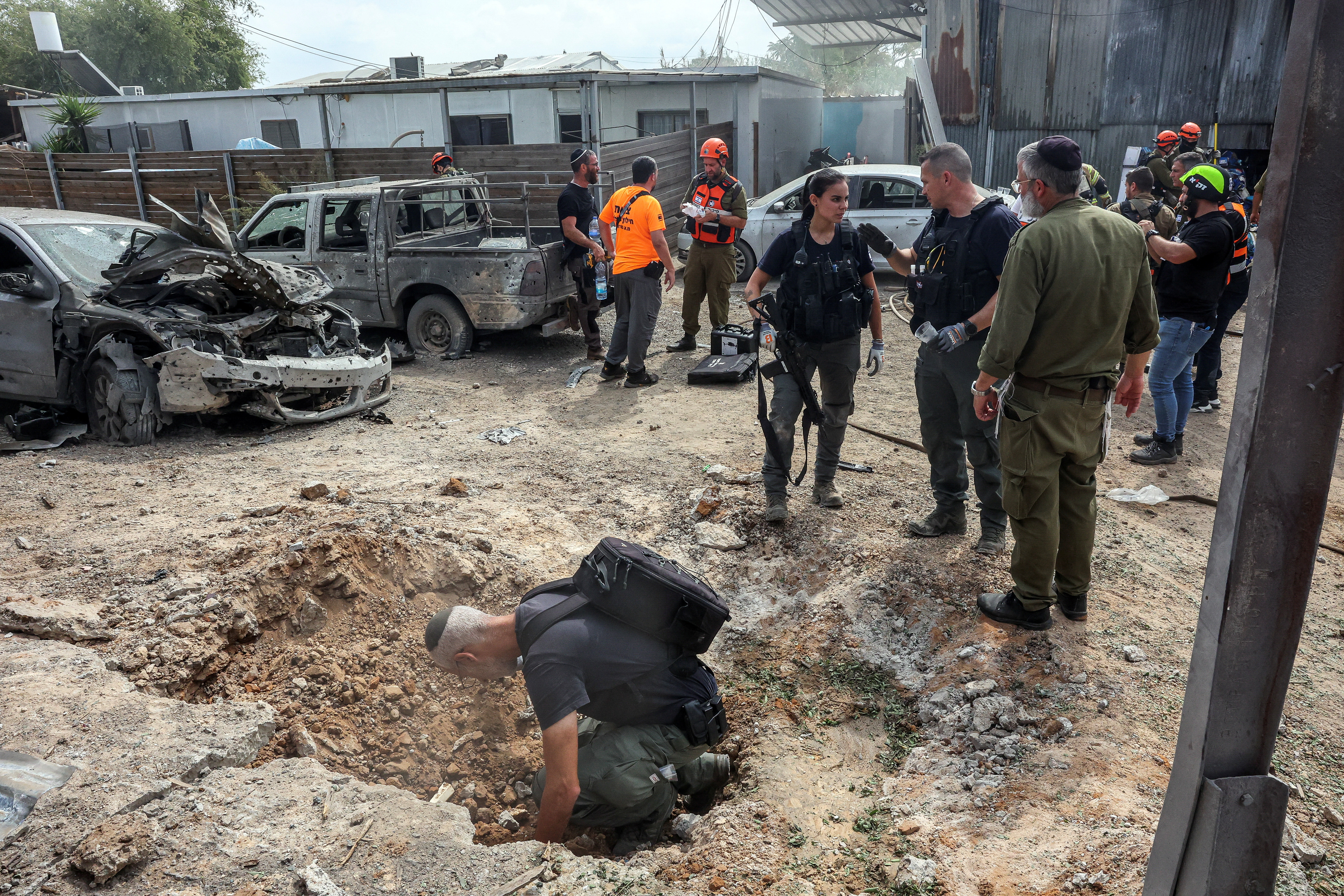 A security official investigates the crater formed when a projectile landed, after Hamas' armed wing said it attacked Tel Aviv with a missile salvo, amid the ongoing Israel-Hamas conflict, in Kfar Chabad