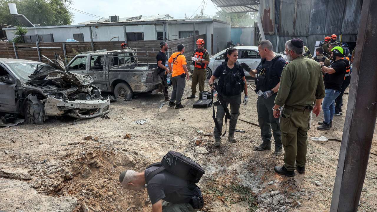 A security official investigates the crater formed when a projectile landed, after Hamas' armed wing said it attacked Tel Aviv with a missile salvo, amid the ongoing Israel-Hamas conflict, in Kfar Chabad