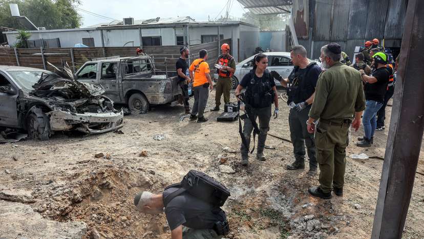A security official investigates the crater formed when a projectile landed, after Hamas' armed wing said it attacked Tel Aviv with a missile salvo, amid the ongoing Israel-Hamas conflict, in Kfar Chabad