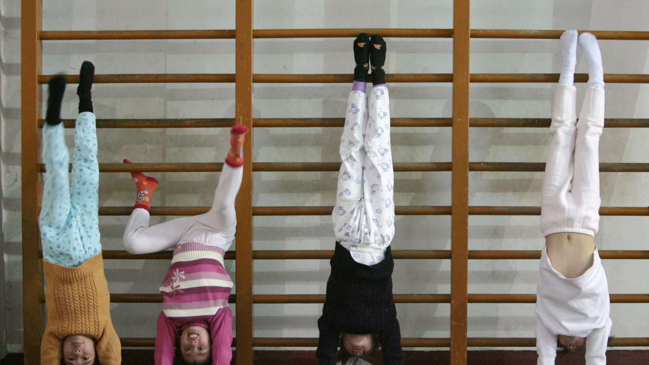 Members of the Nanjing children diving team practise standing on their hands during a training session at a sports college in Nanjing